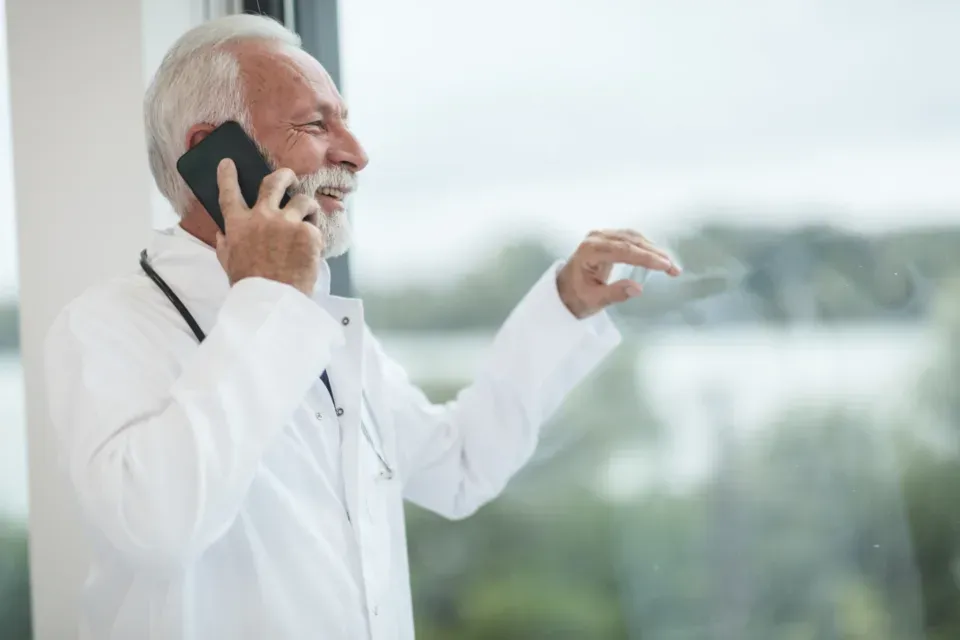 Médecin en blouse blanche au téléphone, de profil