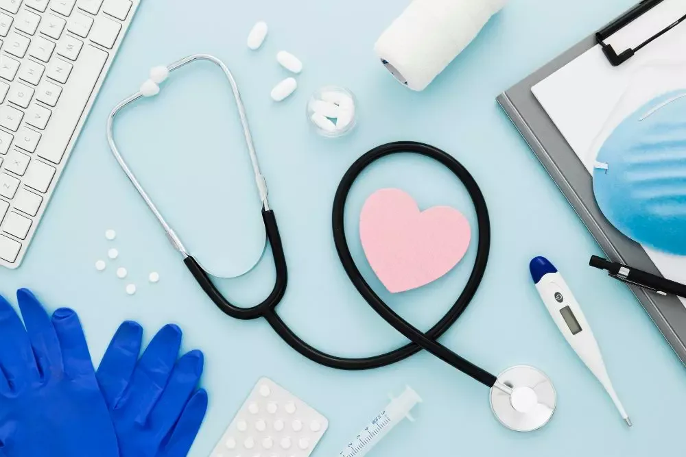 Stéthoscope, cœur en papier, gants et thermomètre disposés sur un bureau