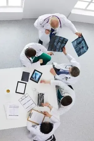 Équipe médicale réunie autour d'une radiographie et d'une tablette